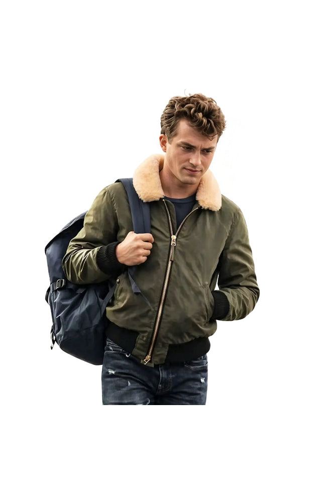 Man wearing a green bomber jacket with a fur-lined hood, holding a blue backpack on a white background