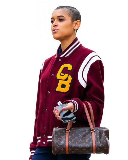 Person wearing a maroon letterman jacket with yellow initials, holding a Louis Vuitton bag.