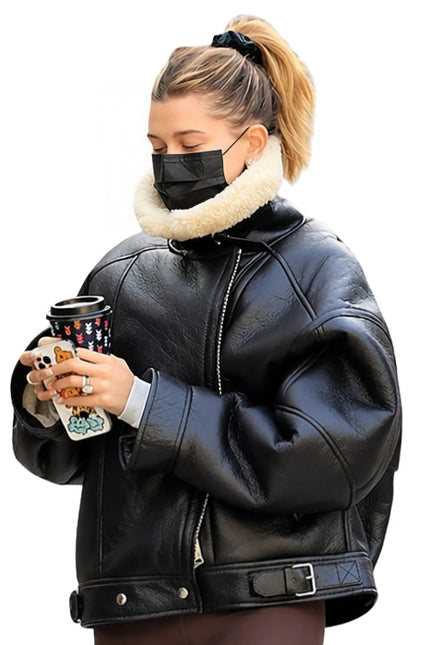 Person wearing a black leather jacket with a white fur collar, holding a Starbucks cup.