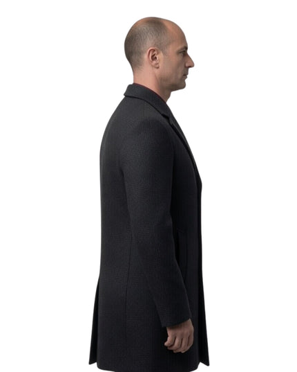 Man wearing a black coat standing against a white background