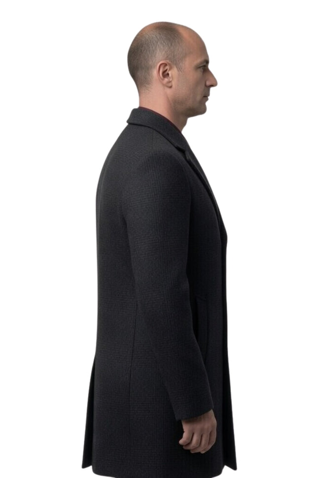 Man wearing a black coat standing against a white background