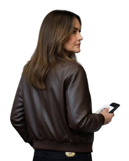 Woman wearing a brown leather jacket holding a phone on a white background