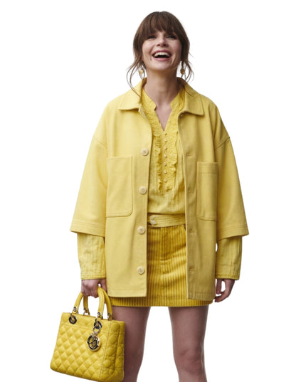 Woman wearing a yellow outfit with a matching handbag on a white background