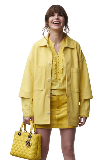 Woman wearing a yellow outfit with a matching handbag on a white background