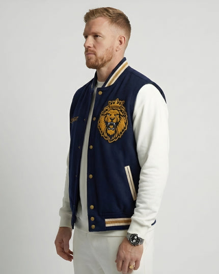 Man wearing a navy blue letterman jacket with a lion emblem on a white background