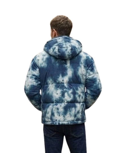 Person wearing a blue tie-dye puffer jacket on a white background