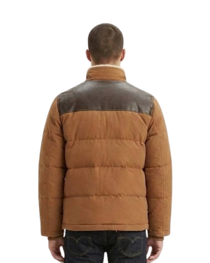 Man wearing a brown puffer jacket with leather accents on a white background