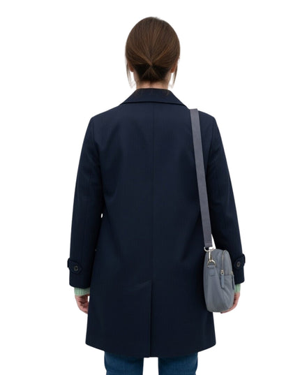 Person wearing a navy coat with a gray bag on a white background
