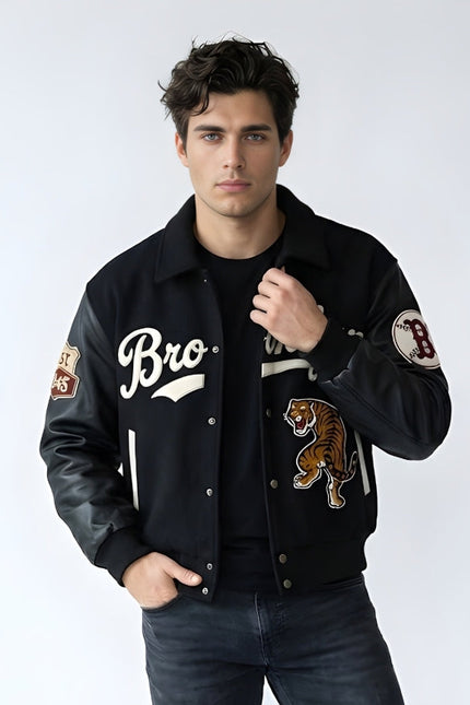 Man wearing a black varsity jacket with patches on a white background