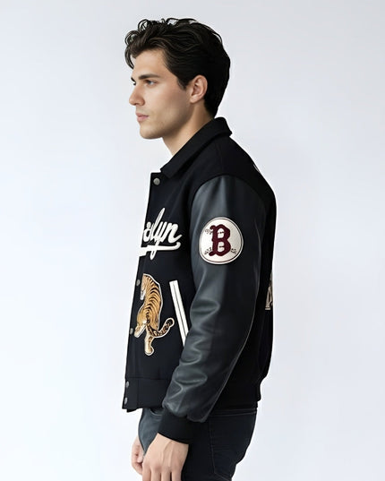 Man wearing a black varsity jacket with patches on a white background