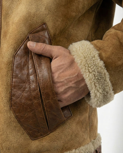Close-up of a hand interacting with a brown leather patch on a shearling coat.