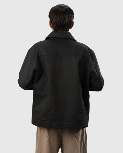 Person wearing a black jacket and beige pants on a white background