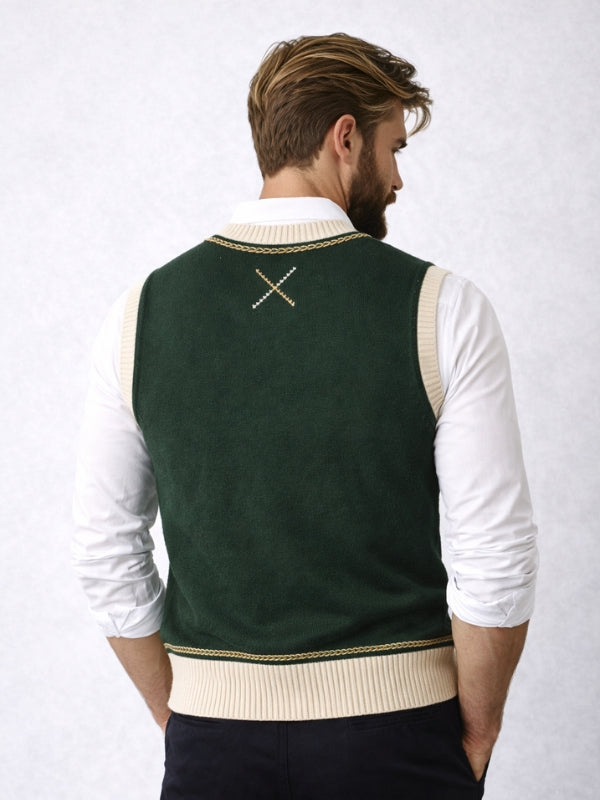 Man wearing a green sweater vest with a white shirt on a light gray background