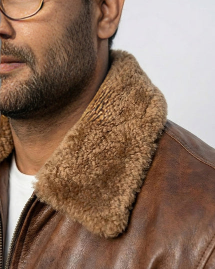 Close-up of a person wearing a brown leather jacket with a fur collar against a light gray background