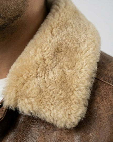 Close-up of a brown leather jacket with a fluffy beige fur collar.