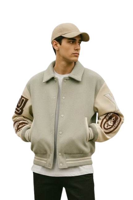 Person wearing a beige varsity jacket with arm patches on a white background
