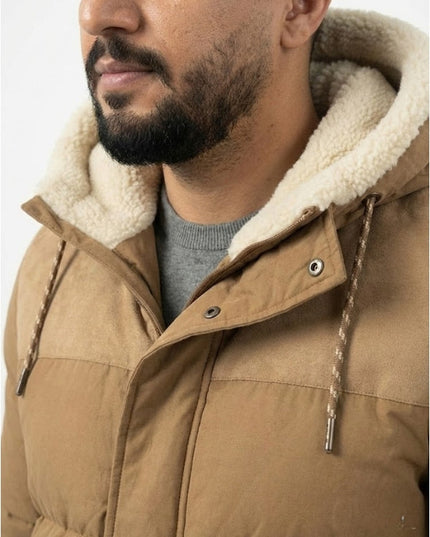 Close-up of a person wearing a brown puffer jacket with a fur-lined hood.