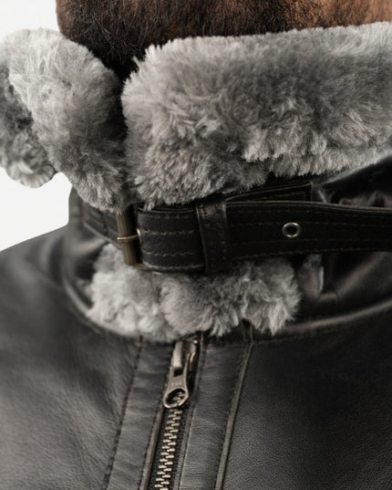 Close-up of a dark leather jacket with a fur-lined hood on a white background