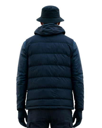 Person wearing a navy blue puffer jacket and hat on a white background
