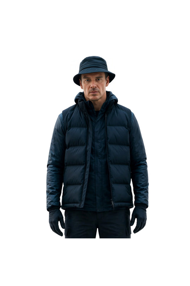 Man wearing a dark blue puffer jacket, hat, and gloves on a white background