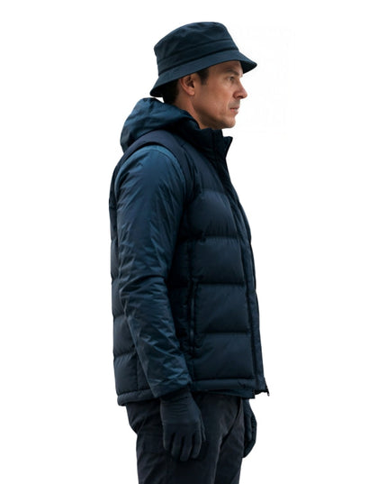 Person wearing a dark blue puffer jacket and hat on a white background