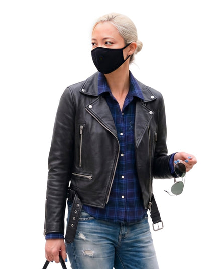 Person wearing a black leather jacket, plaid shirt, and jeans on a white background