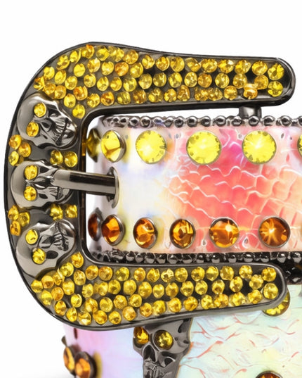 Decorative belt buckle with yellow gemstones and skull designs on a white background