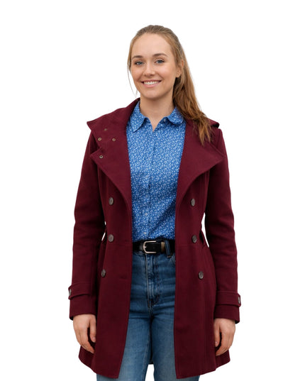 Woman wearing a burgundy coat over a blue shirt and jeans on a white background