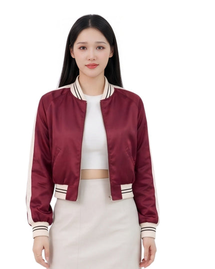Woman wearing a maroon bomber jacket with white accents on a white background