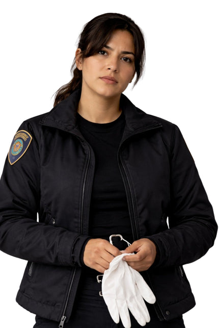 Woman wearing a black jacket with a patch, holding white gloves on a white background