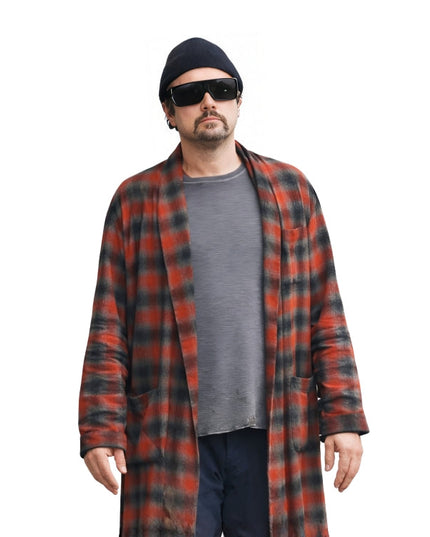 Man wearing a red and black plaid coat over a gray shirt on a white background
