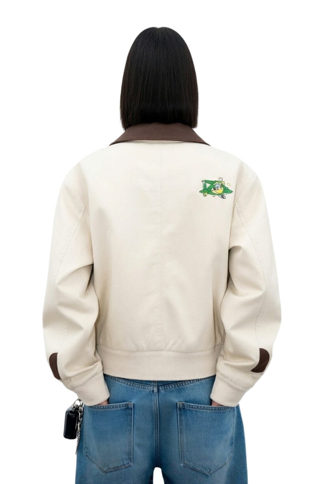 Person wearing a beige jacket with a logo on the back against a white background