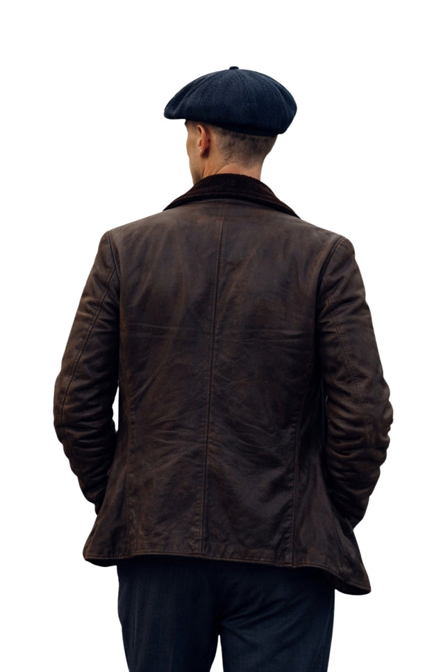 Man wearing a brown leather jacket and black cap on a white background