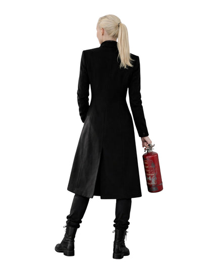 Person wearing a long black coat holding a red fire extinguisher on a white background