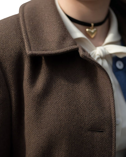 Close-up of a person wearing a brown coat with a white shirt and blue tie.