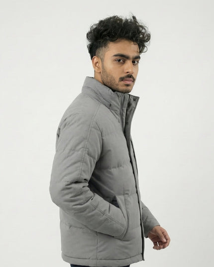 Man wearing a gray quilted jacket on a white background