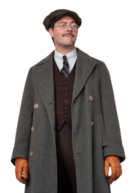 Man wearing a vintage outfit with a long coat, vest, tie, and gloves on a white background