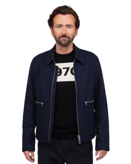 Man wearing a navy jacket over a black t-shirt with white text on a white background