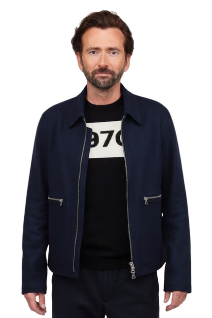 Man wearing a navy jacket over a black t-shirt with white text on a white background