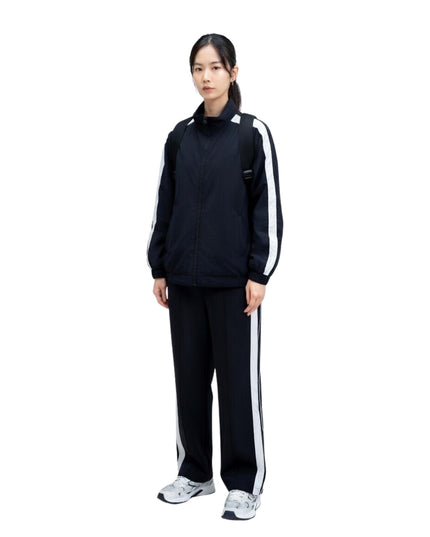 Person wearing a black tracksuit with white stripes on a white background