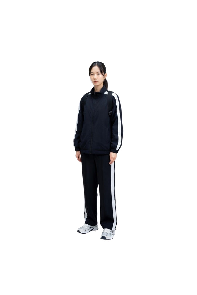 Person wearing a black tracksuit with white stripes on a white background