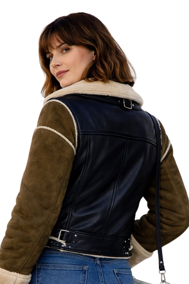 Woman wearing a black and brown leather jacket with shearling trim on a white background