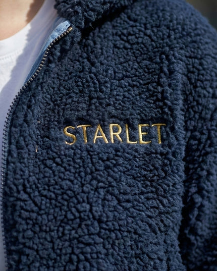 Navy blue fleece jacket with 'STARLET' embroidery on a blurred background