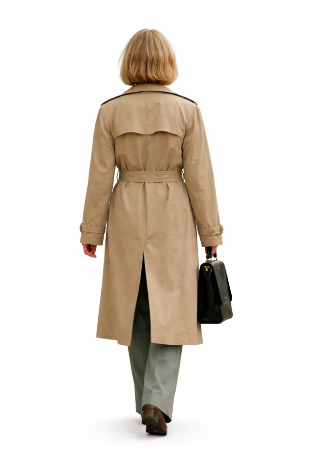 Person wearing a beige trench coat on a white background