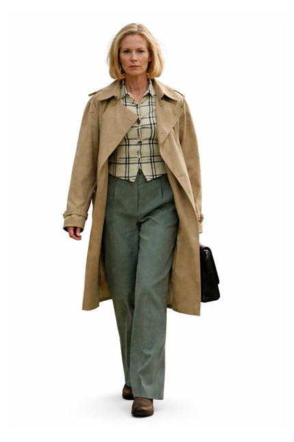 Woman wearing a beige trench coat and green pants on a white background