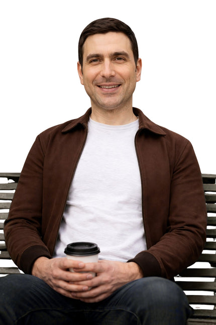 Man sitting on a bench holding a coffee cup against a white background