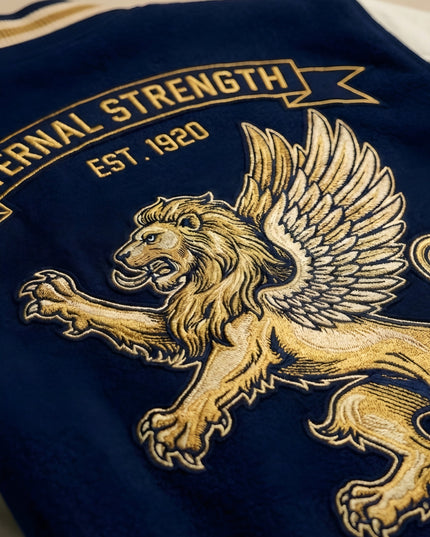 Embroidered lion design on a blue fabric with 'Eternal Strength' text.