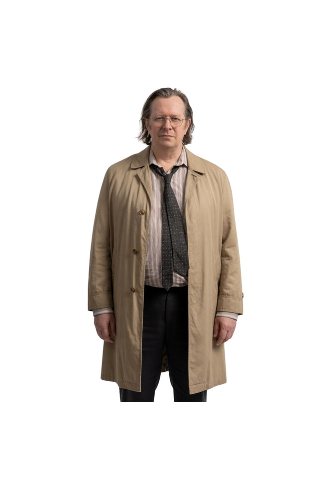 Man wearing a beige trench coat over a suit on a white background