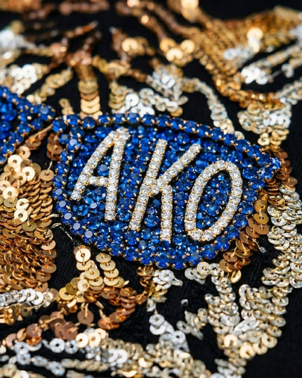 Decorative patch with 'AKO' text surrounded by blue and gold sequins on a black background