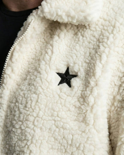 Close-up of a white fleece jacket with a black star patch.